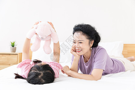 小女孩与奶奶在床上玩娃娃图片
