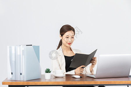 坐在办公桌前看文件的商务女性图片