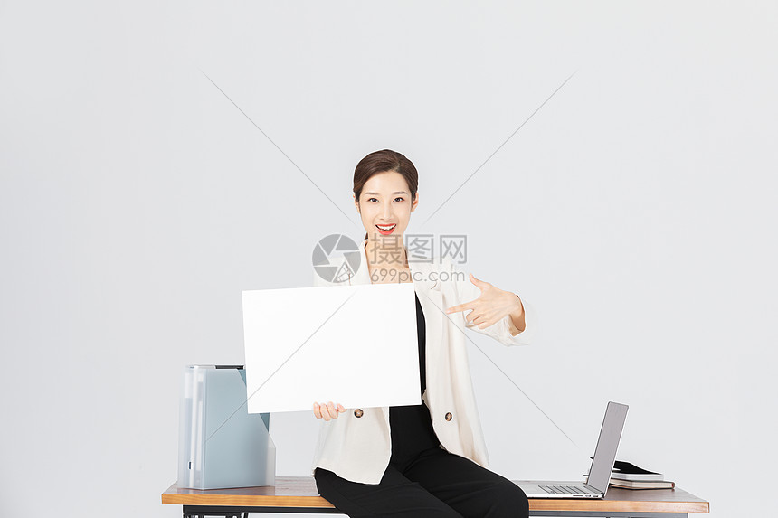 坐在办公桌前拿着白纸的商务女性图片
