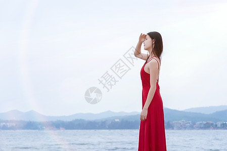 红衣美女深圳较场尾海边礁石上的红衣少女眺望远方侧影背景
