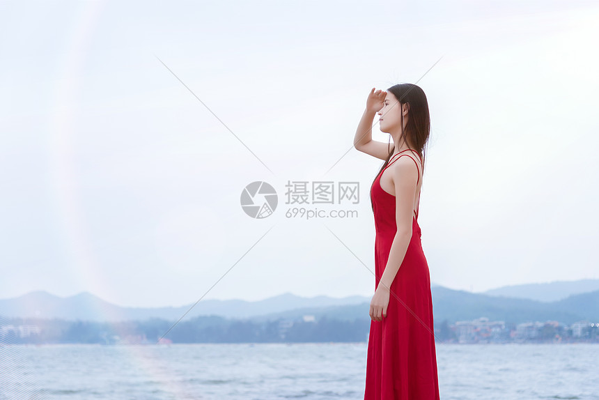 深圳较场尾海边礁石上的红衣少女眺望远方侧影图片