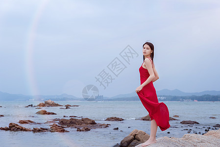 深圳较场尾海边礁石上的红衣少女手拿裙摆图片