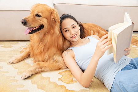 美女躺在狗狗身上看书背景图片