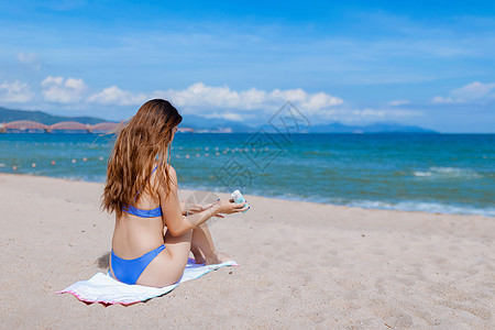 海边美女涂防晒霜背景图片