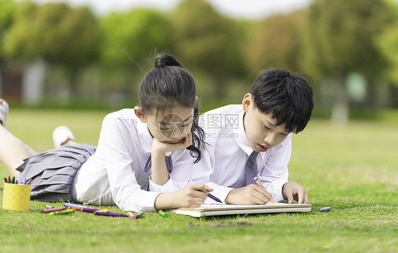 穿校服的学生趴在草坪上画画图片