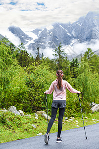 女孩手持登山杖背影图片