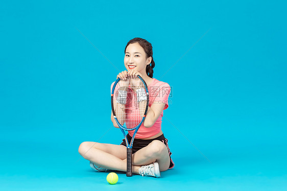 女孩坐在地上拿着网球拍图片