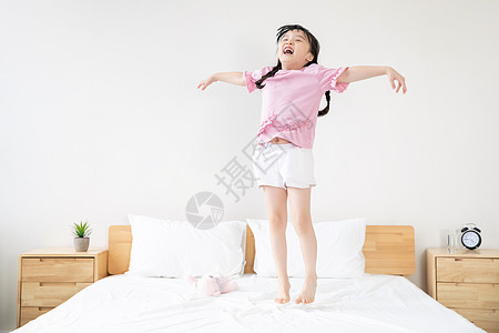 小女孩在床上欢呼跳跃图片