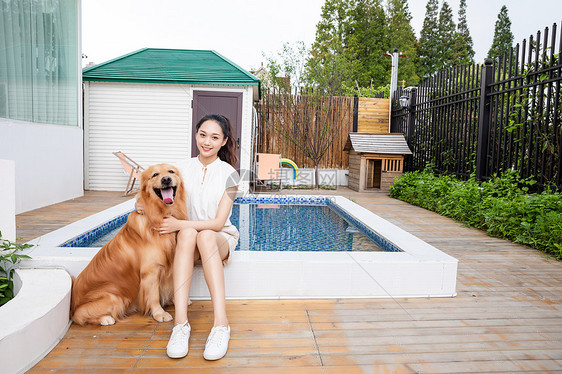 年轻美女与宠物狗院子里嬉戏图片