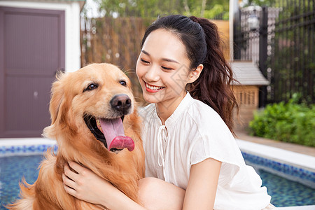 年轻美女主人与宠物金毛犬嬉戏图片