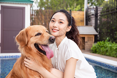 年轻美女主人与宠物金毛犬嬉戏图片