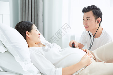 丈夫拿听诊器听孕妇老婆胎动背景图片