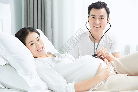 丈夫拿听诊器听孕妇老婆胎动背景图片