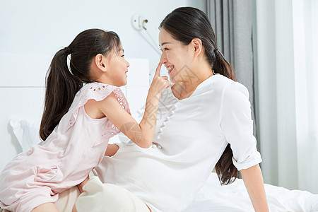 小女孩和孕妇妈妈在床上玩耍图片