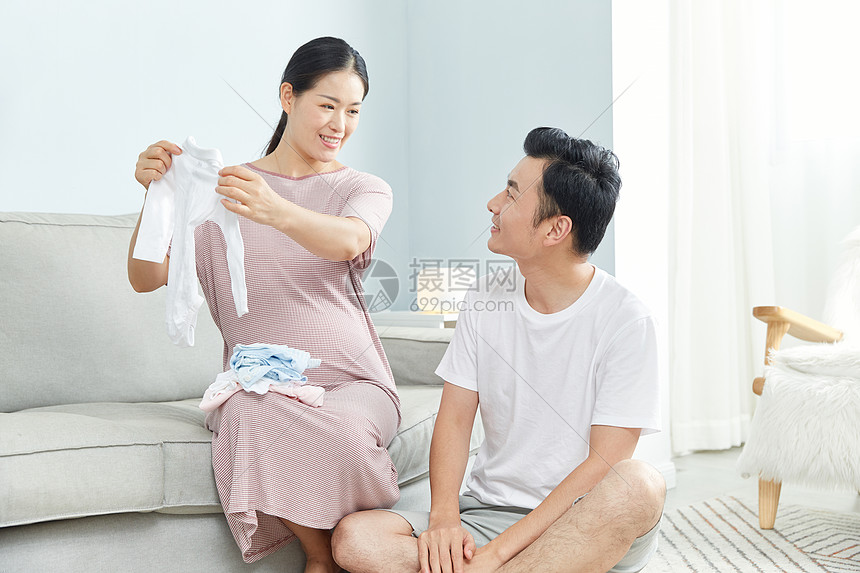 孕妇和丈夫在家收拾婴儿服饰图片