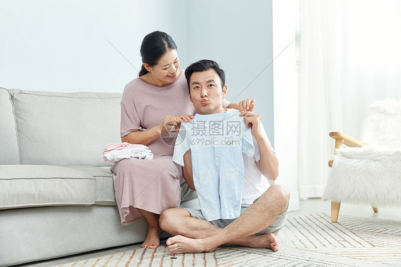 俏皮丈夫和孕妇在家收拾婴儿服饰图片