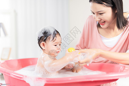 沐浴婴儿妈妈给宝宝洗泡泡浴背景
