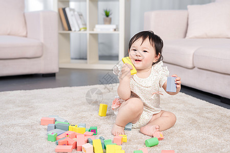 女婴在地毯上玩积木背景图片