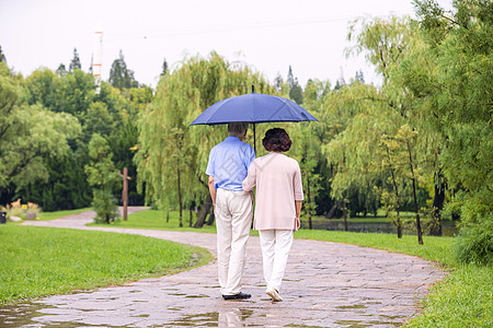老年夫妇在公园雨中漫步背影图片