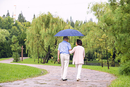 老年夫妇在公园雨中漫步背影图片