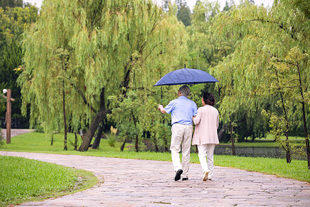 老年夫妇雨中散步背影高清图片