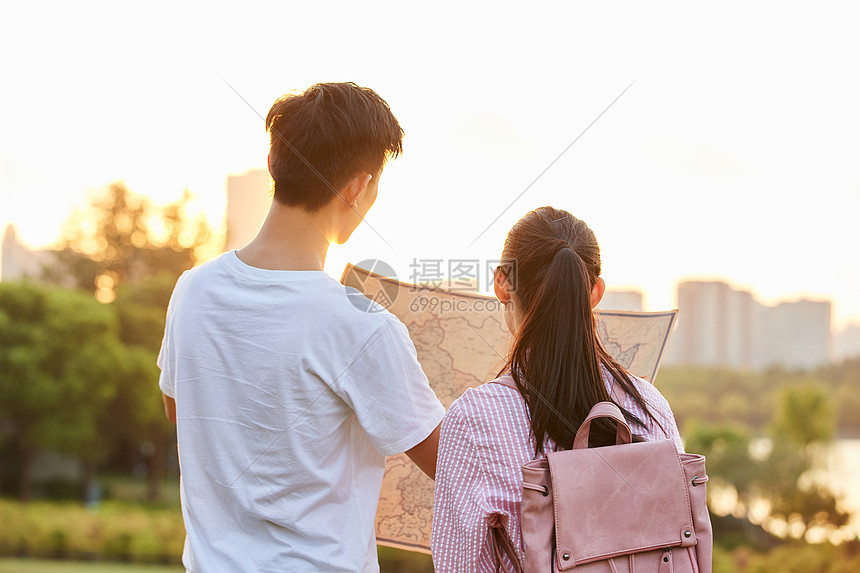 年轻情侣拿着地图旅行背影图片