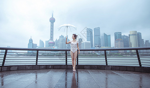 在城市建筑下撑伞的跳芭蕾舞者图片