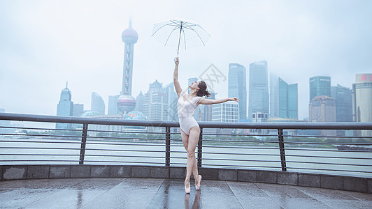 在城市建筑下撑伞的跳芭蕾舞者图片