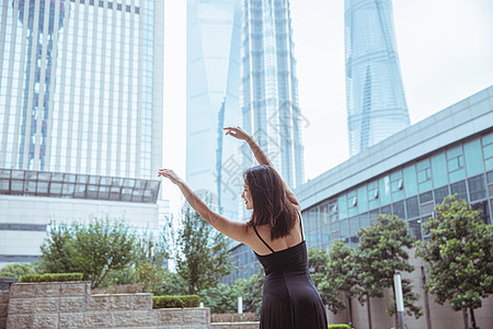 高楼上舞蹈者在城市建筑下舞蹈的女性背景