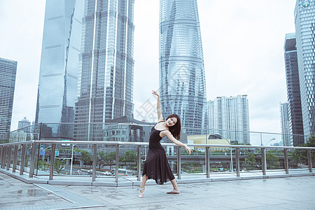 高楼上舞蹈者在城市建筑下舞蹈的女性背景
