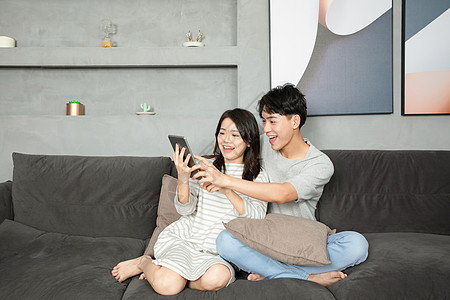 年轻夫妻沙发上玩平板电脑图片