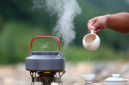 美女手拿烧水壶户外煮茶背景