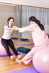 产妇和教练一起练习瑜伽球图片