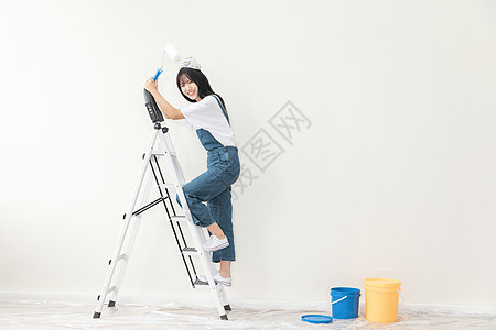 青年女性爬梯子刷墙形象图片
