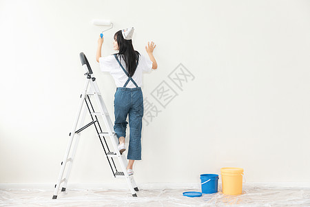 青年女性爬梯子刷墙形象高清图片