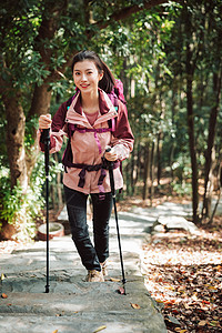 用登山杖爬山的女性形象背景图片