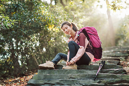 女生坐在山间小路上系鞋带图片