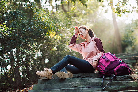 女生坐在山间小路上休息图片