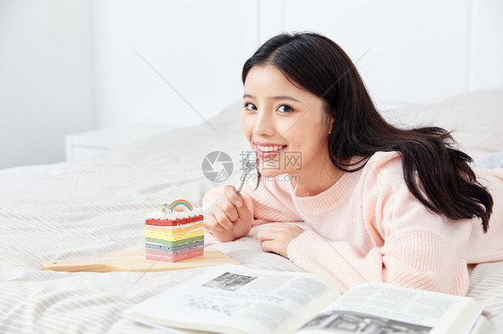 居家美女坐在床上吃蛋糕图片