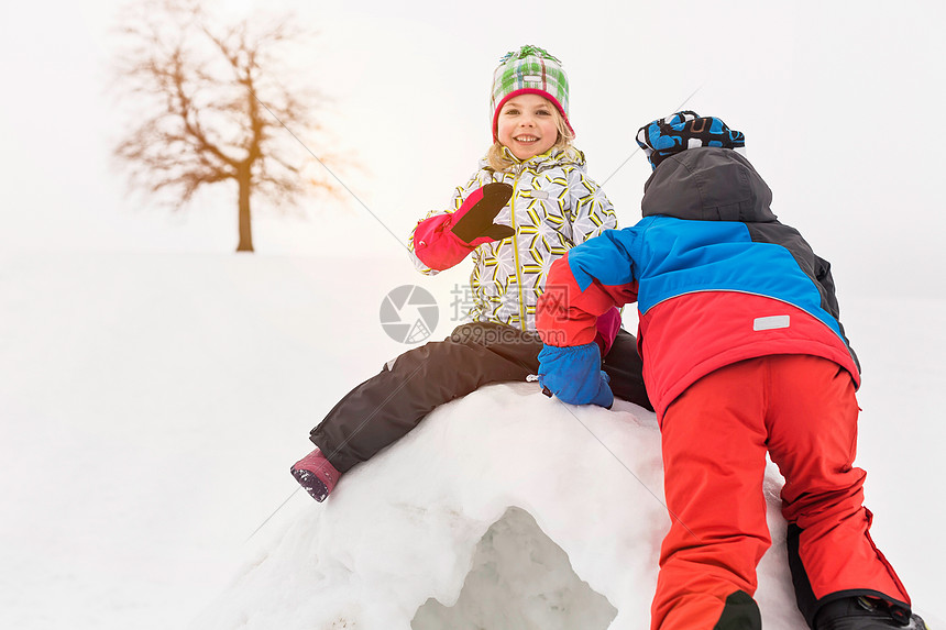 两个孩子在雪屋顶上图片