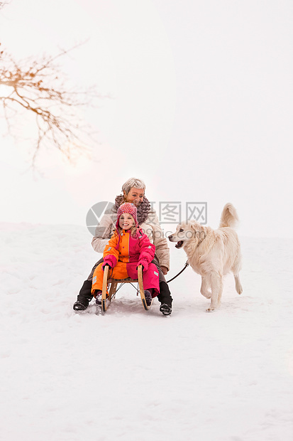 雪中坐雪橇的祖母和孙女图片