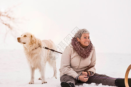 和狗一起坐在雪上的女人图片