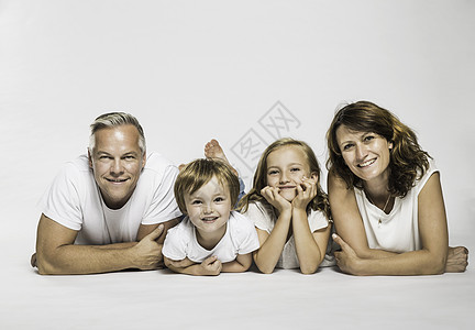 父母和儿子和女儿躺在一起的摄影棚肖像图片