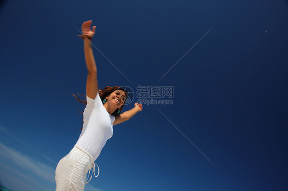 年轻女子在海滩上跳跃图片