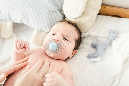 1到6个月母亲触摸婴儿床上的男婴背景