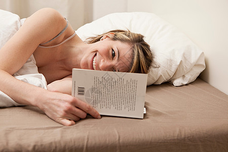 年轻女子在床上看书图片