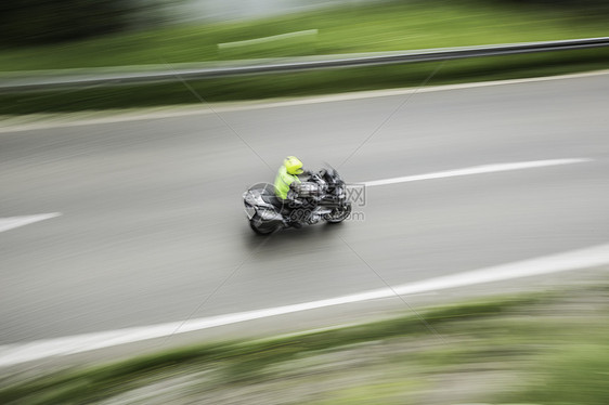 模糊摩托车驾驶员在道路上的大角度视图图片