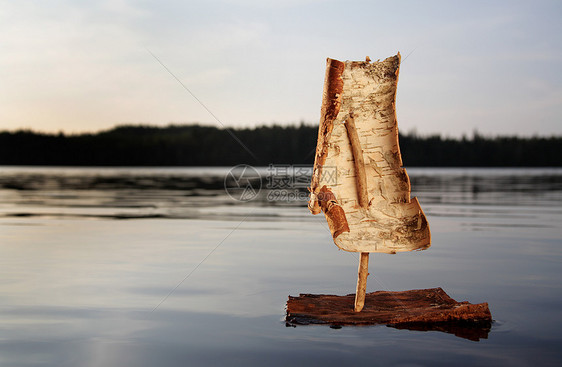 日落时湖面上的树皮船图片
