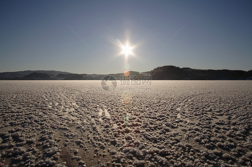 冰封的湖面，太阳低垂在地平线上图片
