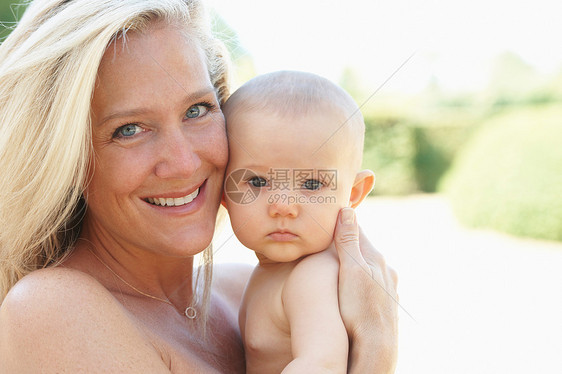微笑的母亲抱着孩子在户外图片